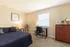 Bright, cozy bedroom with a stylish modern desk, comfy bed adorned with decorative pillows, and a chic wooden dresser, perfect for relaxation and productivity.