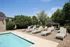 Inviting outdoor pool area with comfortable loungers under a sunny blue sky, surrounded by lush greenery for a relaxing retreat.