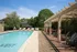 Charming outdoor pool area with stylish lounge chairs and a lush pergola, perfect for relaxation and outdoor gatherings.