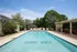 Inviting outdoor pool area at Oxford West, featuring comfortable lounge chairs, lush greenery, and a shaded pergola area for relaxation.