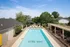 Inviting outdoor pool area at Oxford West with sun loungers, shaded pergola, and lush greenery, perfect for relaxation and leisure.