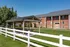 Charming brick apartment complex with a welcoming lawn area and a cozy picnic pavilion under a bright blue sky.