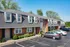 Charming townhouse complex with classic brick facade, stylish dormer windows, and convenient parking spaces set in a lush suburban setting.