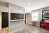 Modern apartment lobby with sleek black mailbox units, stylish wood flooring, a cozy seating area with transparent chairs and a bold red accent shelf.