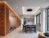 Modern apartment interior featuring an elegant kitchen island, stylish lighting, and cozy lounge area with large windows and decorative brick accents.