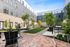 Inviting courtyard oasis with lush greenery, stylish seating, and modern grills in a contemporary apartment complex.