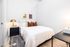 Modern bedroom with stylish decor, featuring a cozy double bed, elegant bedside lamp, and artistic wall prints, exuding warmth and comfort.