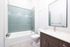 Bright and modern bathroom featuring elegant green tilework, a sleek vanity with mirror, and a pristine bathtub.