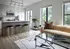 Modern open-concept kitchen and living area featuring sleek cabinetry, stylish bar stools, and floor-to-ceiling windows offering lush green views.