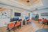 Modern office space with warm wooden flooring, bright orange chairs, and a cozy coffee bar for networking and relaxation.
