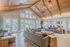 Spacious and inviting living room with vaulted wooden ceilings, large windows offering natural light, and stylish modern furniture arrangements.