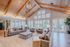 Inviting and elegant living room with high wooden ceilings, plush sofas, modern lighting, and large windows overlooking a serene outdoor space.
