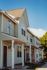 Charming row of modern townhouses with inviting porches, set against a clear blue sky, offering a cozy suburban vibe.