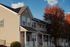 Charming townhouse exteriors with crisp siding and inviting porches, set against a backdrop of vibrant autumn foliage and blue sky.