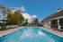 Inviting outdoor pool area with elegant lounge chairs, vibrant foliage, and clear blue sky, perfect for relaxation and enjoyment.