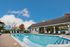 Inviting outdoor pool area with lounge chairs, surrounded by beautiful landscaping and a charming clubhouse under a bright blue sky.