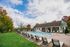 Inviting outdoor pool area with modern lounge chairs, surrounded by lush greenery and a charming clubhouse, perfect for relaxation.