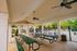 Inviting outdoor pavilion with ceiling fans and picnic tables, perfect for gatherings, overlooking a refreshing swimming pool and lush greenery.