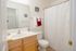 Bright and modern bathroom with a large mirror, sleek vanity, and stylish chevron shower curtain. Cozy and welcoming color scheme with vibrant red and white towels adding a touch of elegance.