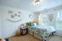 Bright and cozy bedroom with colorful bedding, elegant wall decor, and ample natural light through large windows.
