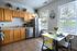 Bright and inviting kitchen featuring modern stainless steel appliances, light wood cabinetry, and a cozy dining nook with cheerful decor.