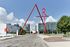 Vibrant cityscape featuring modern architecture and a striking red art sculpture under a bright blue sky.
