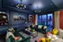 Chic living room with elegant blue cabinetry, vibrant decor, plush green sofas, and large windows opening to a scenic patio.