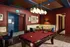 Chic apartment entertainment room with a sleek billiards table, elegant lighting, and cozy seating areas, perfect for leisure and gatherings.