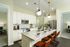 Elegant, modern kitchen with a spacious marble countertop, sleek white cabinetry, and stylish pendant lighting creating a warm ambiance.