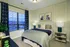 Cozy bedroom with elegant decor, featuring a plush bed, chic artwork, and large window offering natural light.