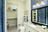 Modern bathroom with elegant blue tile accents, granite countertop, spacious walk-in shower, and organized shelving.