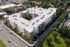 Aerial view of a modern, expansive apartment complex with lush landscaping, ample parking, and a vibrant urban setting.
