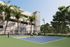 Modern outdoor tennis court surrounded by lush greenery and palm trees, offering a vibrant, sporty lifestyle in a residential area.