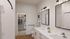 Elegant bathroom with a white marble countertop, featuring dual mirrors and ample natural lighting. Spacious walk-in closet is visible in the background, enhancing the luxury apartment's modern appeal.