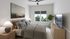 Inviting bedroom with elegant decor, featuring a cozy bed, chic wooden dresser, and large window with a scenic view, complemented by a modern ceiling fan.