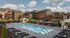 Luxurious apartment complex featuring a pristine swimming pool, elegant lounge chairs, and vibrant landscaping, perfect for relaxation and enjoyment.