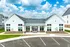 Charming modern apartment complex with inviting clubhouse and pristine landscaping, set against a vibrant blue sky.