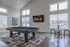 Modern entertainment room with a sleek billiards table, contemporary art, cozy fireplace display, and stylish seating area.