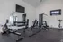 Modern fitness center featuring sleek exercise equipment, free weights, and a spacious workout area with mirrored walls.