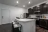 Modern kitchen with sleek dark cabinetry, stainless steel appliances, and a spacious island with stylish bar stools.