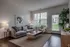 Inviting living room with modern gray sofa, elegant artwork, and large windows bringing in natural light, complemented by chic decor and a peaceful exterior view.