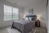 Bright and inviting bedroom with a comfortable queen-sized bed, elegant decor, and an abundance of natural light through large windows.