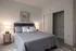 Cozy bedroom featuring a plush gray bed, elegant side tables with lamps, and a spacious open closet.