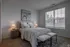 Inviting bedroom with a cozy bed, modern artwork, and large windows welcoming natural light.