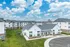 Modern apartment community featuring sleek white buildings, lush green lawns, and a bright, open sky, offering a serene suburban living experience.