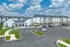 Charming apartment complex surrounded by lush green lawns, offering ample parking and modern architecture under a picturesque sky.