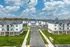 Charming aerial view of a modern apartment complex with beautifully landscaped grounds and ample parking spaces, set under a picturesque blue sky.