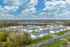Scenic aerial view of a modern apartment complex surrounded by lush greenery, showcasing a peaceful suburban community with spacious living options and convenient roads for easy access.