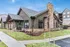 Charming modern building with rustic stone accents and lush green landscaping against a bright blue sky.