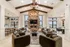 Elegant living room with vaulted ceilings, exposed wooden beams, a stone fireplace, and chic modern furniture for a cozy ambiance.